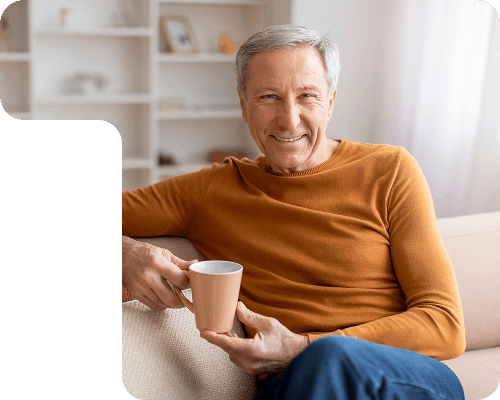 Elderly man smiling while holding a cup of coffee